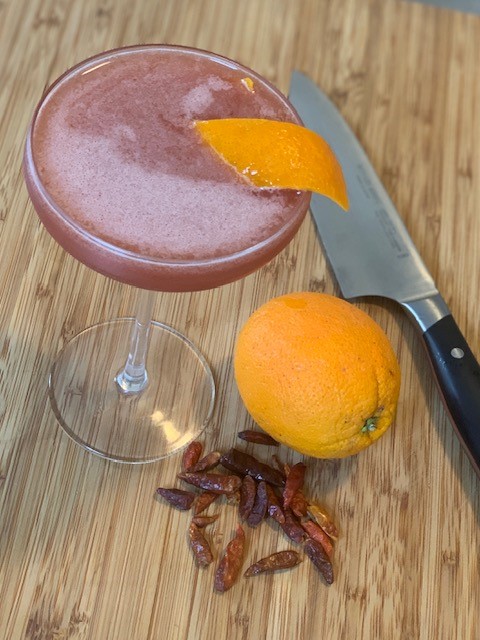 a cocktail with orange slices and a knife