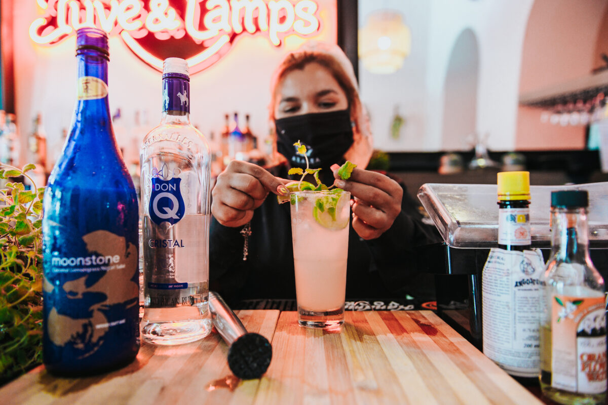 a woman in a mask preparing a cocktail