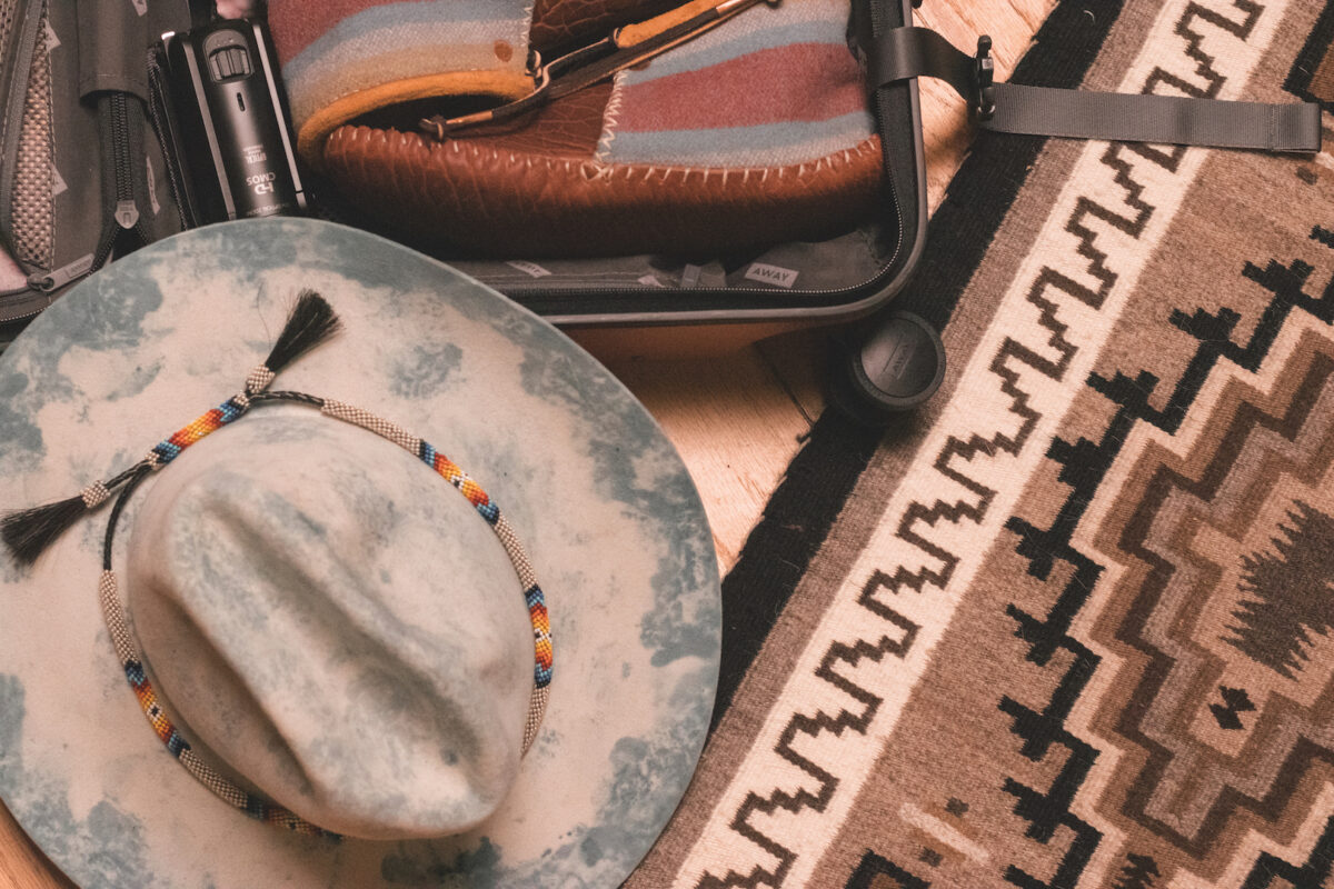 a hat and a packed suitcase on a rug