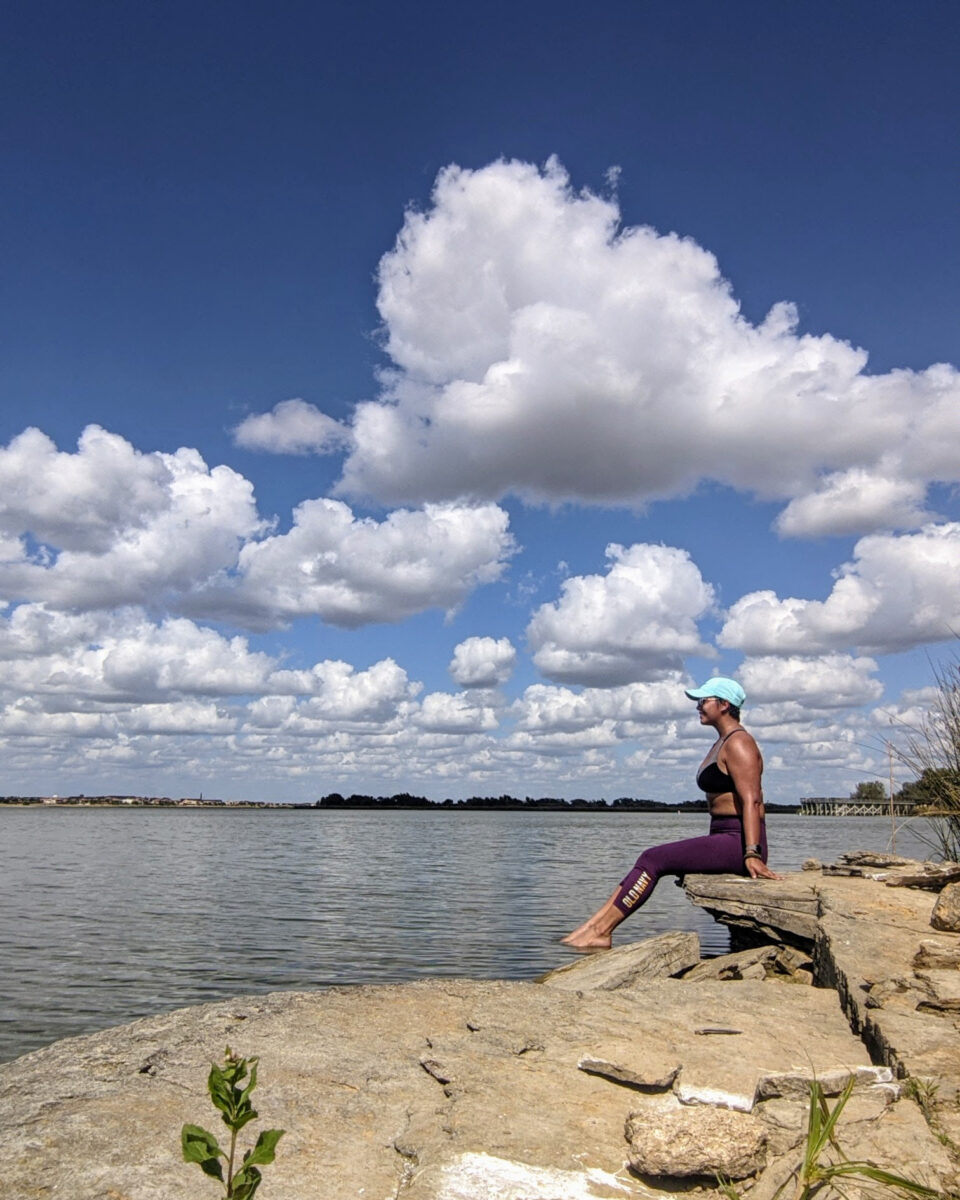 a woman sitting on a lake's edge