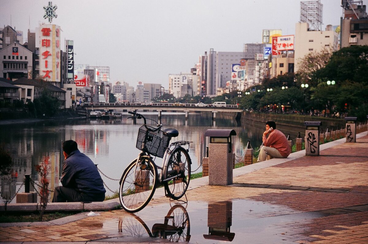 people sitting with bikes along a river